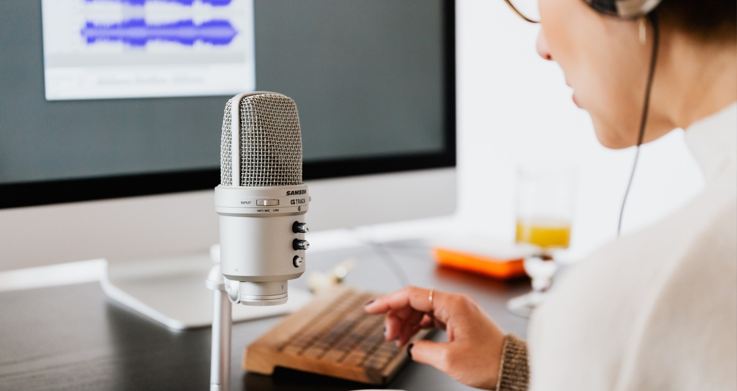  Gemini said A podcaster is shown from a side profile, wearing headphones and working at a desk with a professional Samson G-Track microphone and a computer. The monitor in the background displays an audio waveform, capturing a clean and modern workspace dedicated to high-quality audio production and digital content creation.