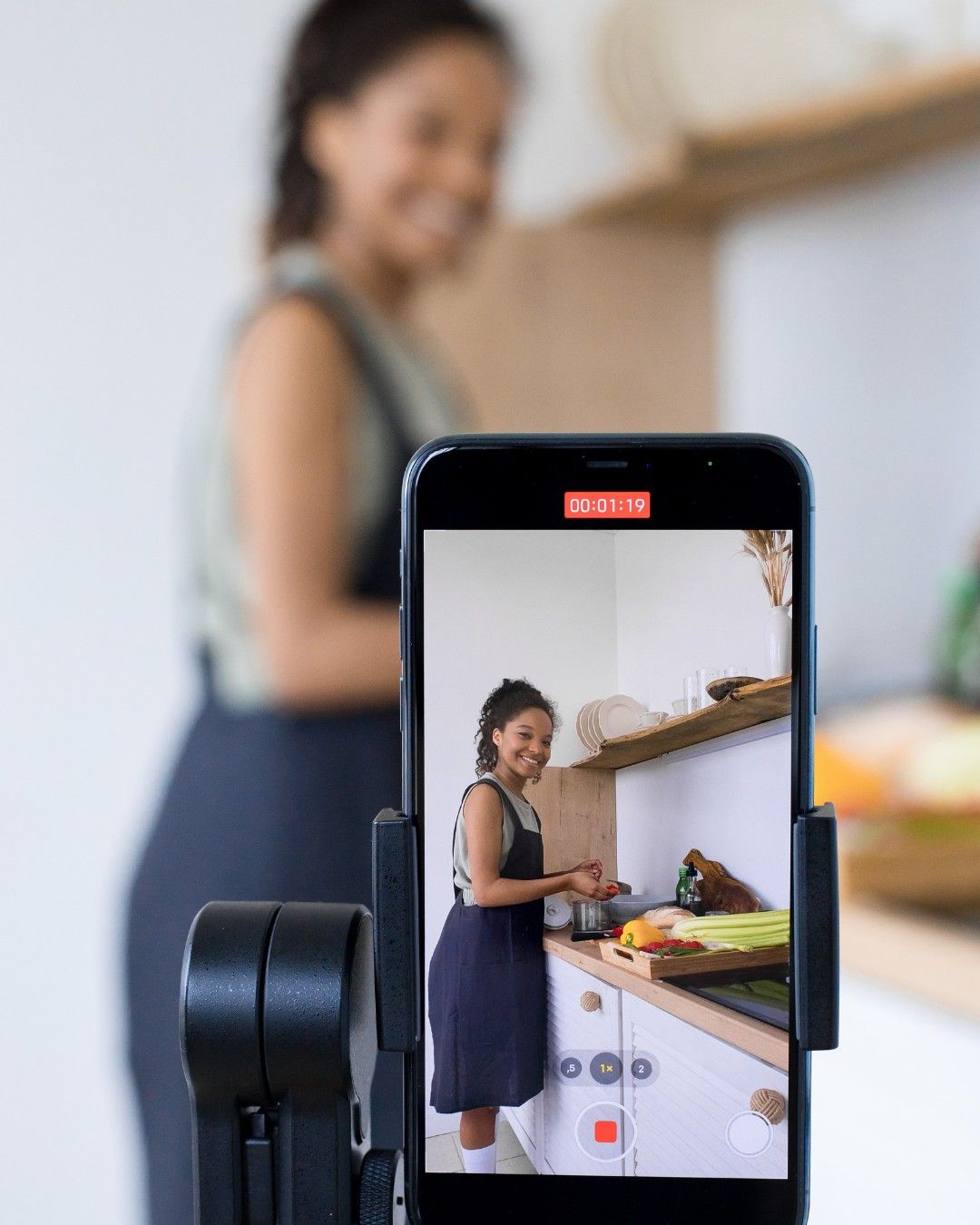 A young woman with her hair in two buns holding up a pink Instagram notification bubble icon showing 341 likes while pointing at it against a solid pink background.