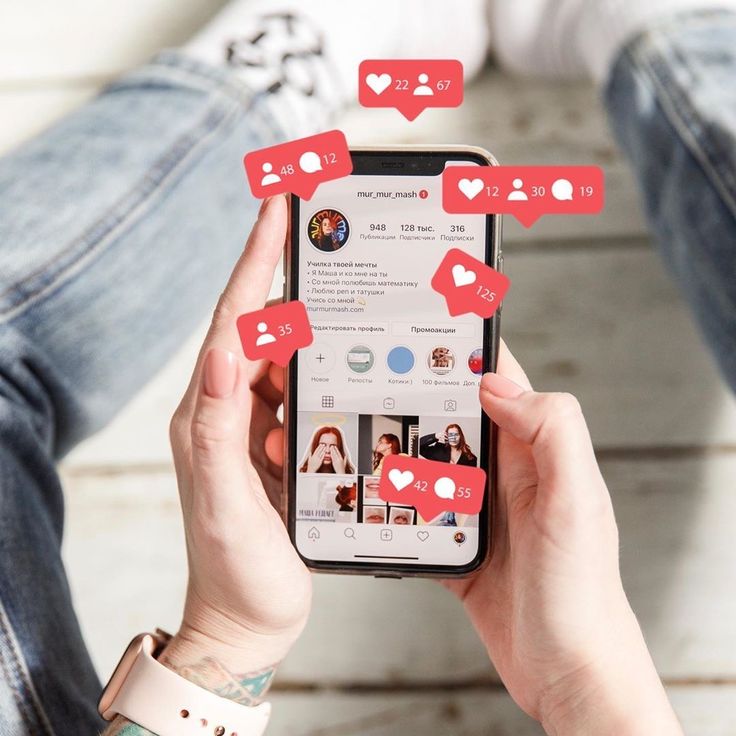 A person wearing blue jeans and a smartwatch holds a smartphone displaying an Instagram profile page. Several stylized 3D red notification bubbles float around the phone, highlighting incoming alerts for likes, comments, and new followers.