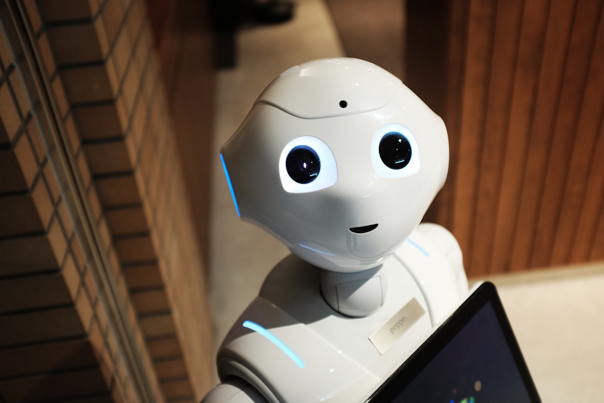 A white humanoid robot — AI agents are starting to operate the faceless posting pipeline, not just generate its content (photo: Unsplash)