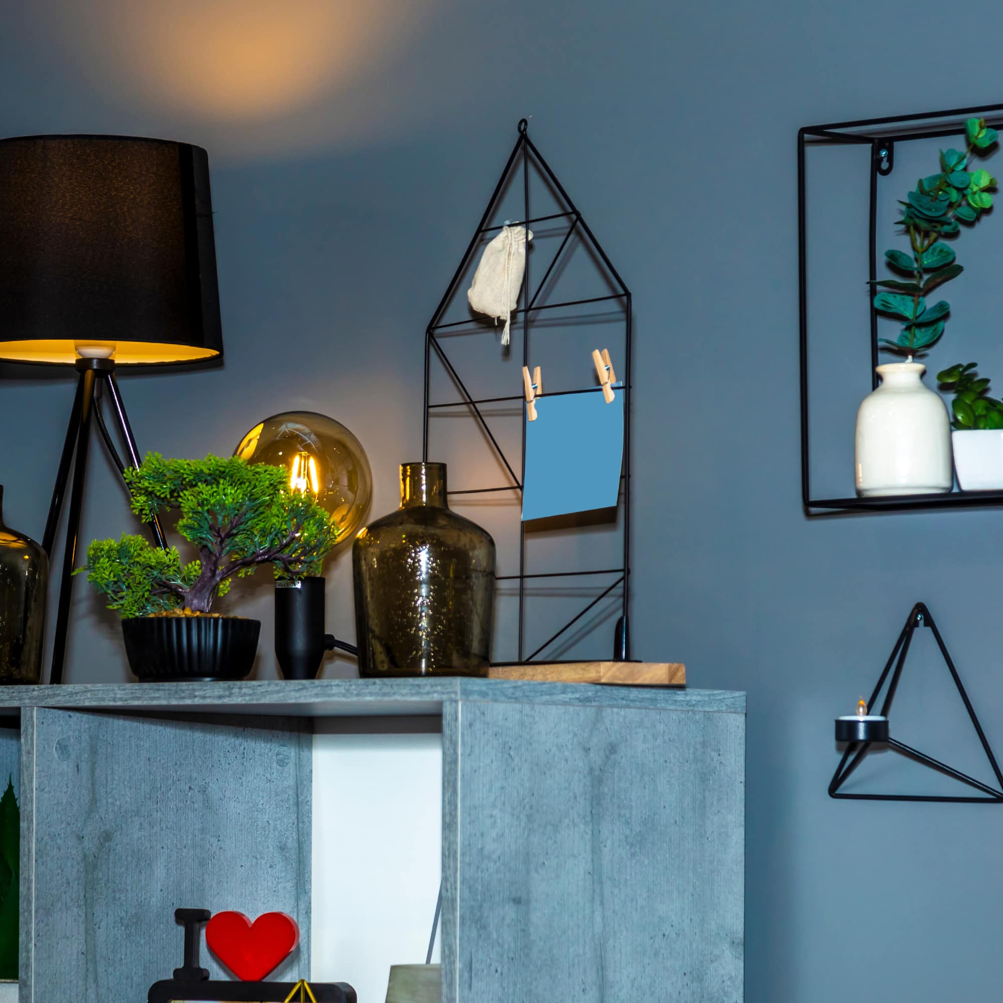 A male spa therapist in scrubs standing beside a massage table with skincare products and candles in a calm, softly lit spa setting.