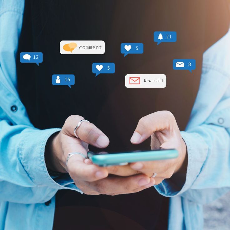 A close-up of a person's hands holding and typing on a smartphone. Floating above and around the phone are various digital social media notification icons, including speech bubbles for comments, hearts for likes, envelopes for new mail, and follower alerts, many of which display a notification count number.