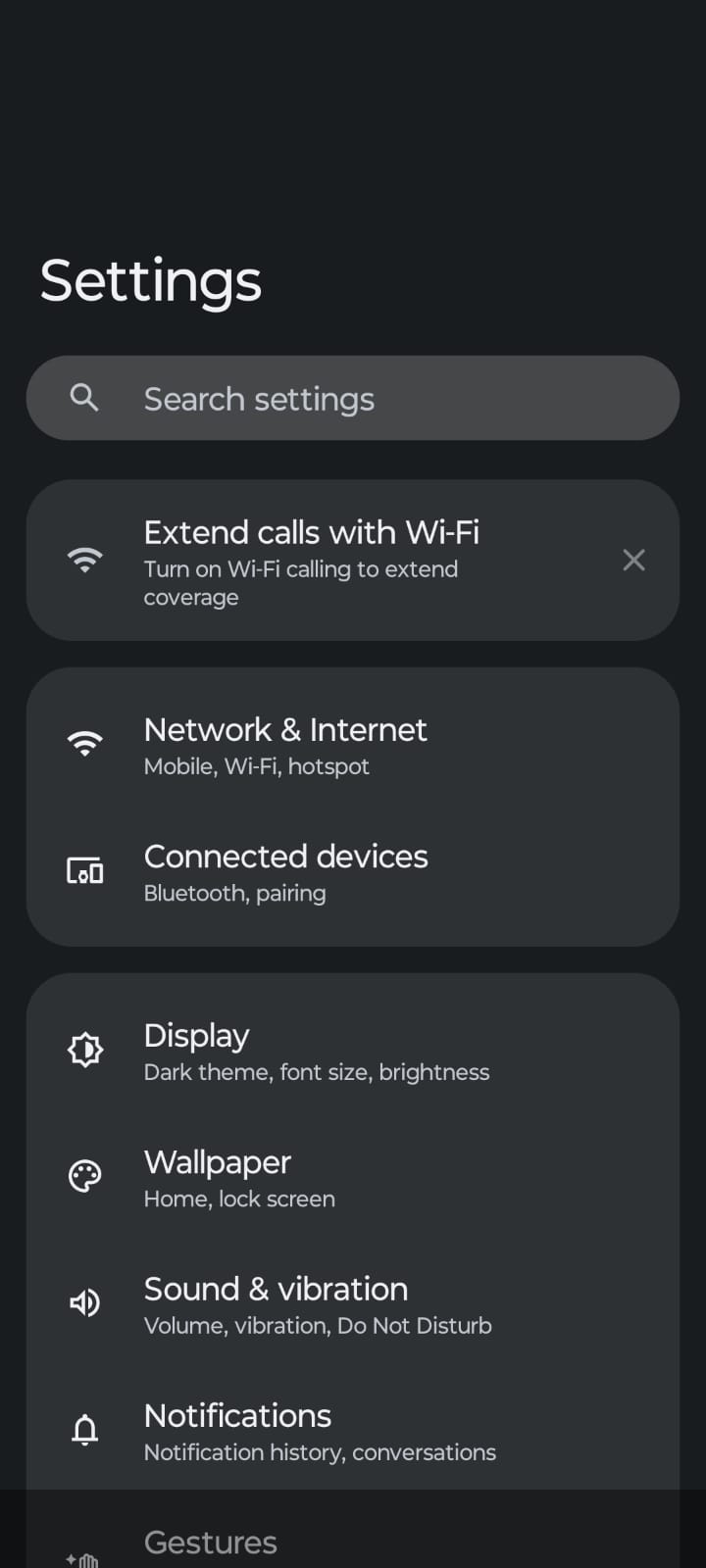 Screenshot of an Android Settings screen in dark mode, showing options such as Network & Internet, Connected Devices, Display, Wallpaper, Sound & Vibration, Notifications, and Gestures, with a search bar at the top.