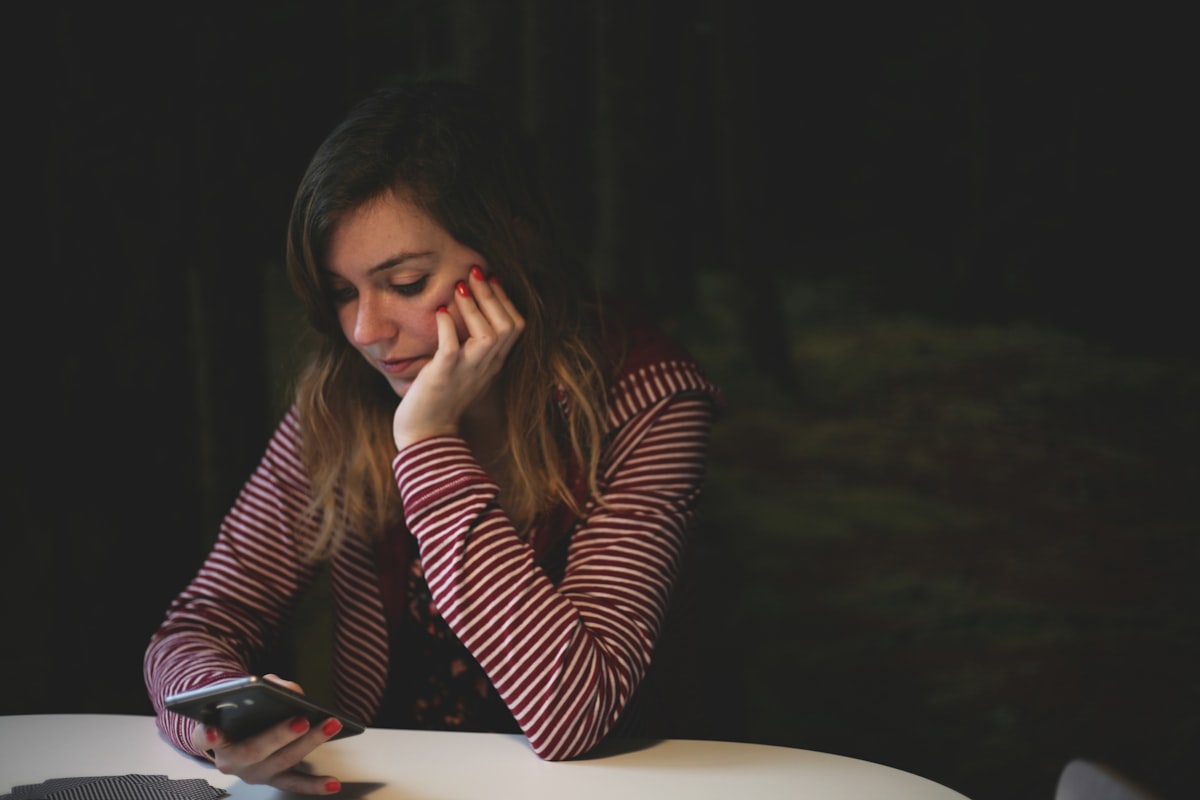 A worried person staring at their phone in the dark: the moment you find your Instagram account restricted or disabled.