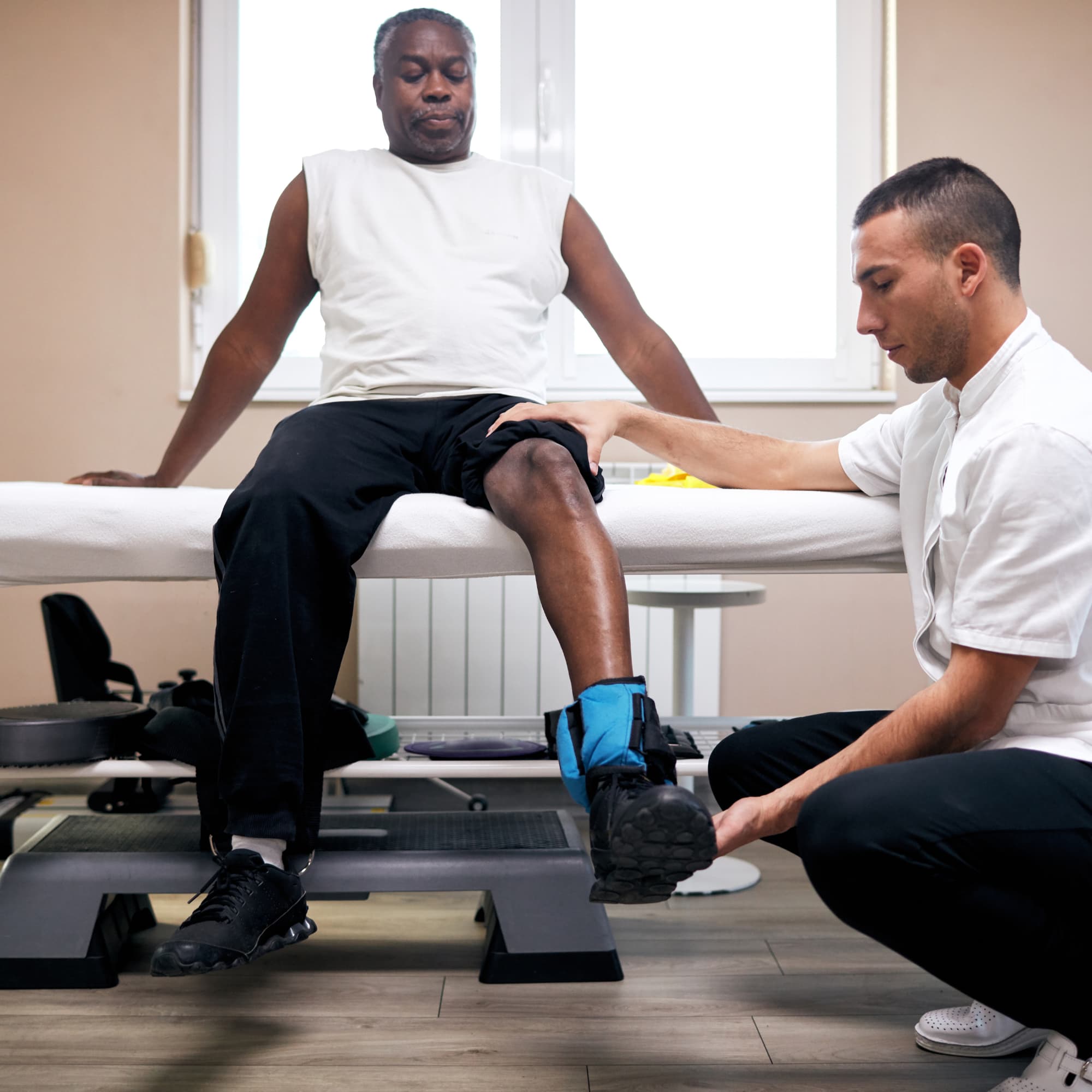 A physical therapist assisting a patient with a leg brace during a rehabilitation session, focusing on knee support and recovery in a clinical setting.
